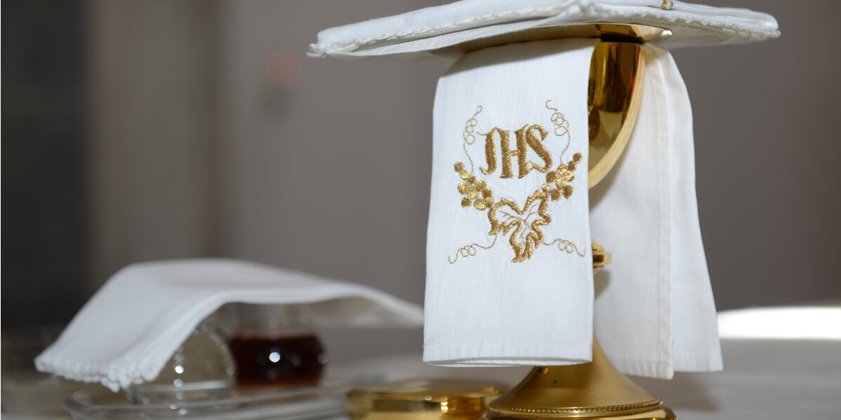 A gold cup covered in a white fabric trophy displayed on a table inside a Catholic chapel in Mykonos wedding