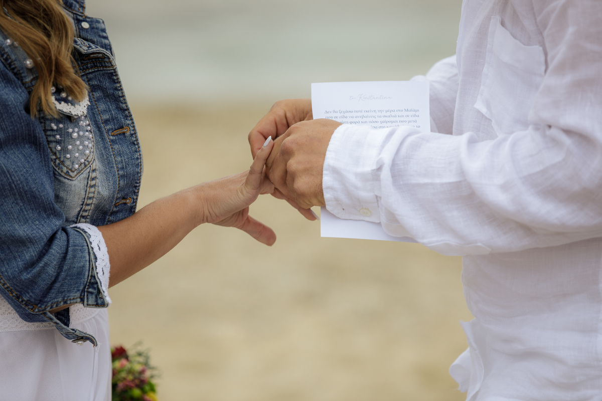 groom placing a ring on brides finger on a wedding ceremony at the beach at a destination wedding in Mykonos