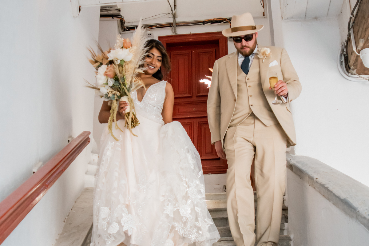  A bride and groom gracefully descend a staircase of Mykonos Town hall, after having their civil wedding ceremony in Mykonos