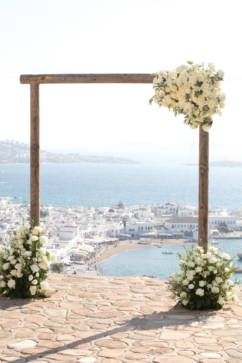 An enchanting Mykonos wedding ceremony at a beautiful venue, featuring a romantic setting with vibrant flowers and sea views.